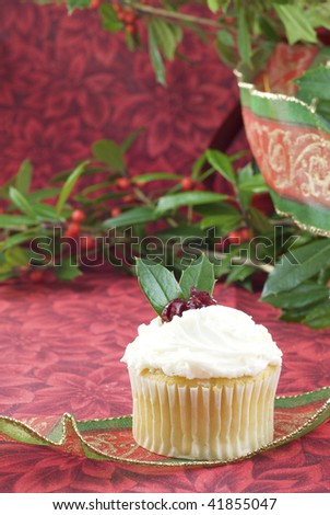 A delicious festive holiday cupcake on a vertical background with holly and ribbons, selective focus, copy space