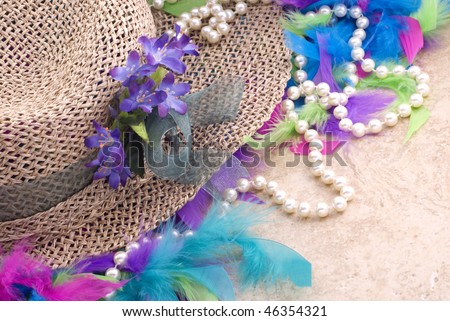 A straw Easter hat with flowers, a colorful feather boa and pearls on a horizontal vintage background with copy space, perfect for Easter or Mother\'s Day
