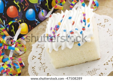 A piece of white party cake with colored sprinkles and festive party decorations, horizontal with copy space