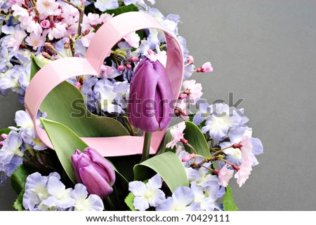 A pretty pastel spring bouquet with a metal pink heart decoration, horizontal with textured background