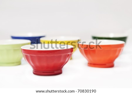 A set of colorful bowls, with selective focus on red bowl, white background with copy space, abstract