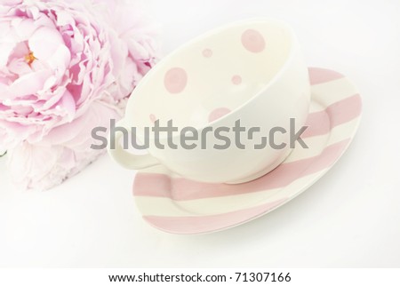 An empty tea cup with a pink Peony in the  background with shallow depth of field, copy space