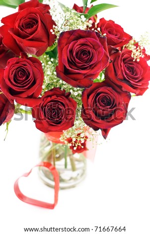 A bouquet of deep red roses in a vase with red heart shape, shallow depth of field with selective focus