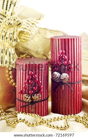 Two red Christmas candles with gold gift box and gold decorations, vertical with white copy space