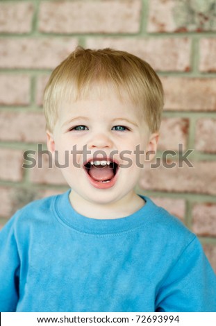 A cute little boy with blond hair with his mouth wide open, selective focus with focus on face