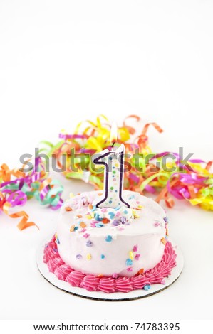 A party cake with one lit candle and party ribbons, selective focus, low key