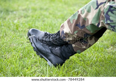 A US Army soldier wearing camouflage resting with just a closeup of his legs and boots, selective focus on boots