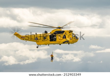 DAWLISH, UNITED KINGDOM - AUGUST 23, 2014: Royal Navy Sea King Search and Rescue Helicopter Flying at the Dawlish Airshow Demonstrating Winch Rescue