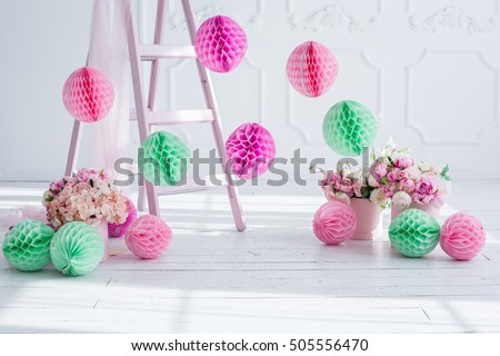 The original bright decor for birthday girl.Pink and green decorative paper balls. White Room decorated with flowers and paper decorations for party. Small white rabbit