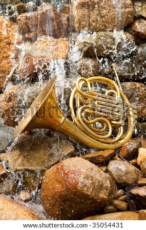 Brass French Horn on a rock in a waterfall