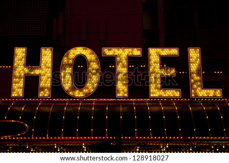 hotel sign lit up by light bulbs at night