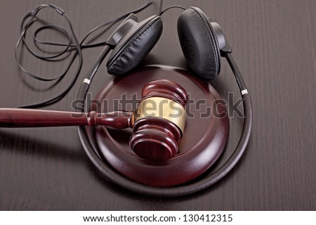 Concept image about music piracy and copyright protection law featuring  a gavel and headphones on tabletop