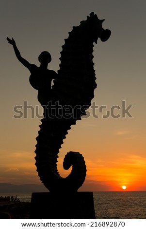 Sunset in Puerto Vallarta with the silhouette of a sea horse riding mermaid  in the foreground