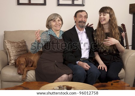 grandparents and granddaughter having a good laugh together sitting on a couch with the family dog