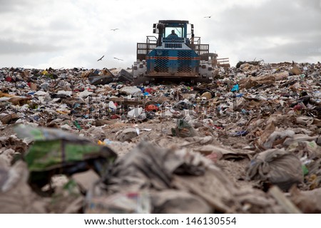 Garbage piles up in landfill site each day while truck covers it with sand for sanitary purpose