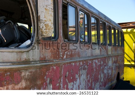 A view of an wrecked bus in a junkyard