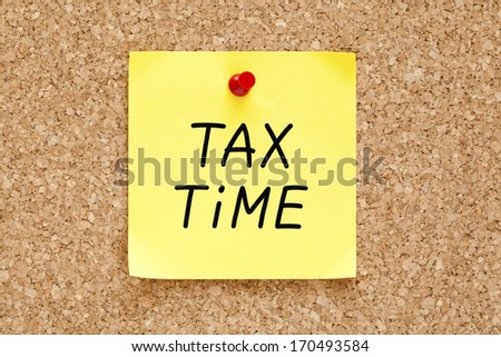 Tax Time Written On Yellow Sticky Note Pinned With Red Push Pin On Cork Board.