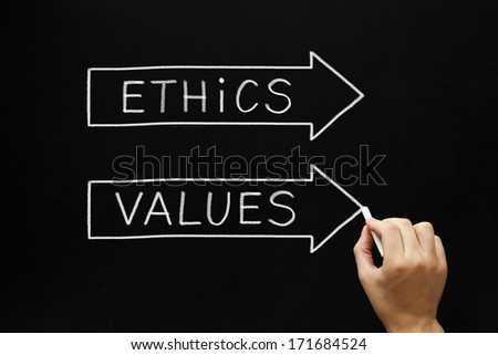 Hand sketching Ethics and Values arrows concept with white chalk on a blackboard.