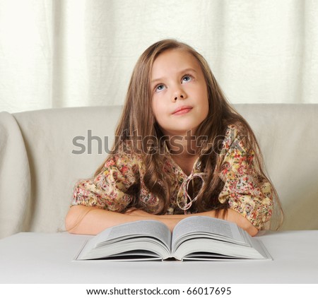 Little girl dreams about something when reading the book.