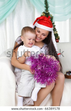 Mum and son near a christmas fur-tree opens the gift