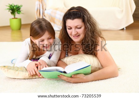 Young mom reads a book for child on a floor