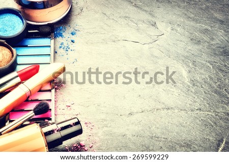 Various makeup products on dark background with copyspace