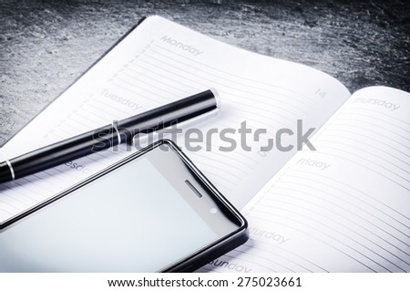 Business concept with agenda, mobile phone and pen
