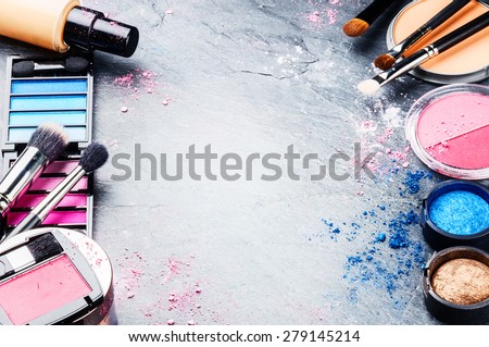 Various makeup products on dark background with copyspace