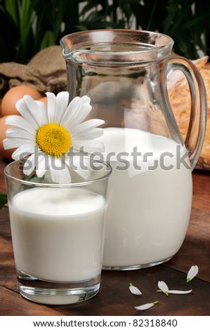 Pitcher of milk with daisy on a wooden table