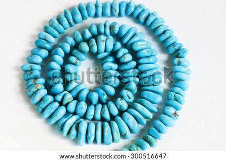 A strand of oval shaped turquoise pieces that have been polished and arranged in a spiral pattern