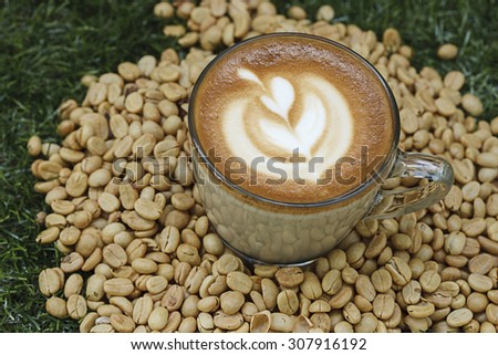 A cup of coffee with flower shape milk foam on coffee bean background