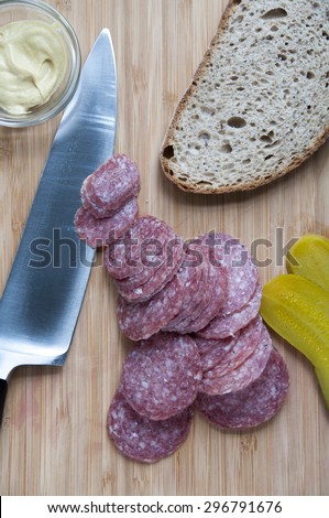 Sliced salami with bread and pickles