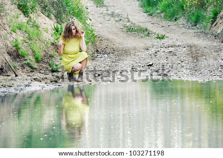 Portrait of a beautiful blonde girl, dressed with a green dress, near a lake