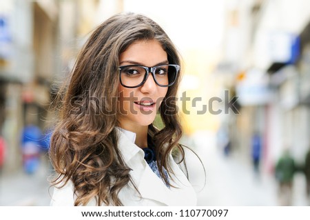 Portrait of a beautiful woman with eye glasses smiling in urban background