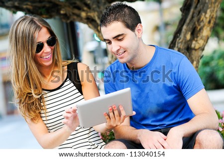 Portrait of attractive couple with tablet computer in urban background