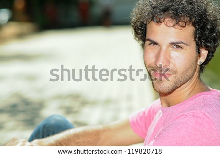 Portrait of handsome man with curly hairstyle smiling in urban background