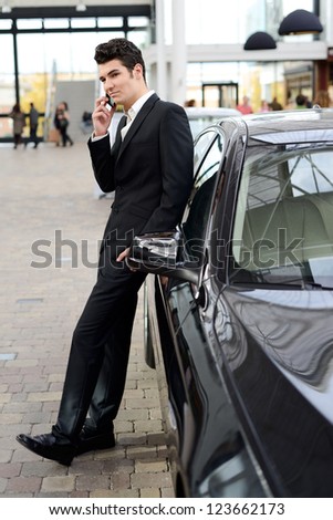 Portrait of a young handsome man, model of fashion, wearing suit and with luxury car