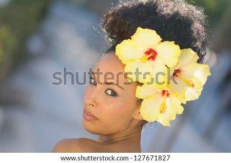 Portrait of a young black woman, model of fashion, with big flowers in her hair