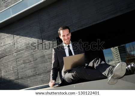 A businessman sitting on the floor with a laptop computer, rising his arm