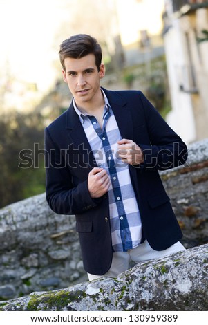 Portrait of handsome man with modern hairstyle smiling in urban background