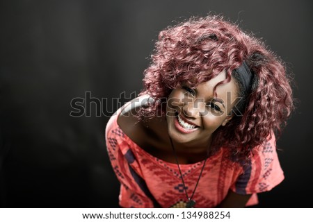 Portrait of beautiful black woman on black background with red hair. Afro hairstyle. Studio shot