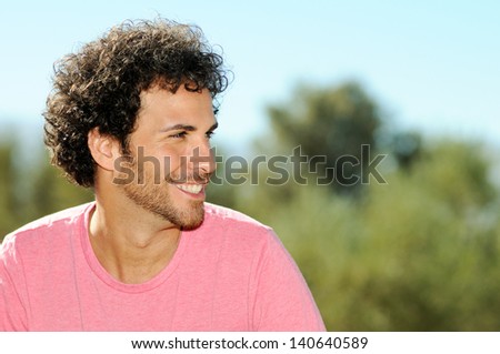 Portrait of handsome man with curly hairstyle smiling, outdoors