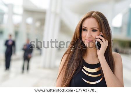 Portrait of beautiful young woman in urban background talking on phone and smiling