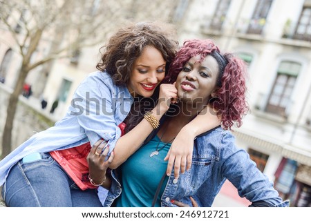 Portrait of two beautiful girls in urban background, black and mixed women. Friends talking