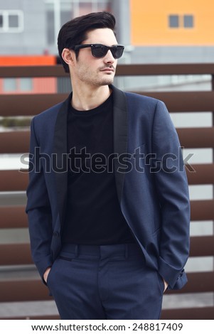 Portrait of an attractive man, model of fashion, wearing modern suit and sunglasses.