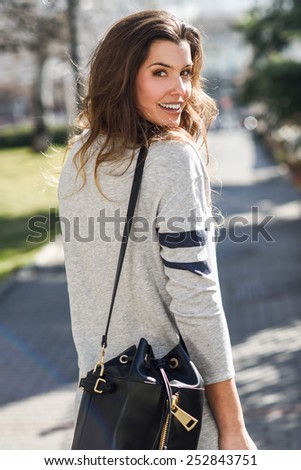 Portrait of beautiful woman smiling, wearing casual clothes in urban background