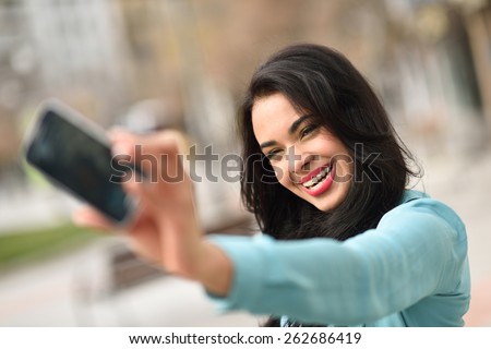 Portrait of a beautiful young woman, using braces, selfie in the street with a smartphone