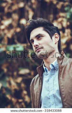 Portrait of a young handsome man, model of fashion, with modern hairstyle in urban background, wearing casual clothes.
