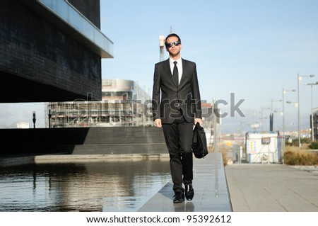 Portrait of a attractive young business man walking in the street with a briefcase