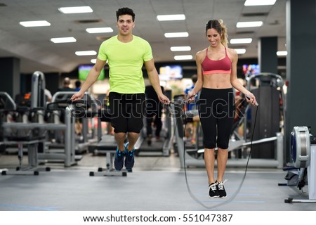 Handsome man and beautiful sporty woman workout with jumping rope in crossfit gym